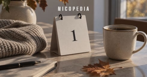 Kalender som visar 1, kaffekopp och löv på ett bord.